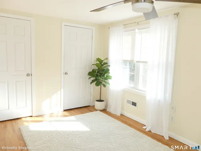 a view of empty room with wooden floor and fan