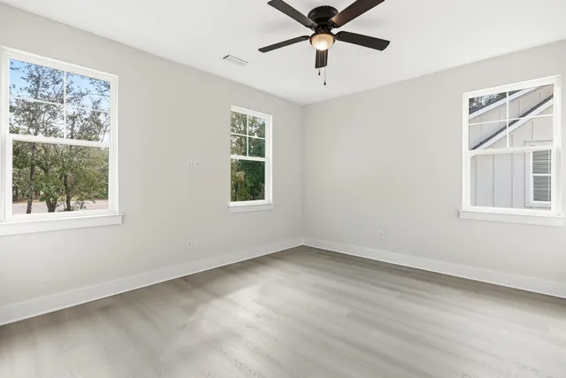 a view of an empty room with a window and wooden floor