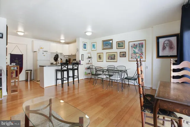 a living room with furniture and kitchen view with wooden floor