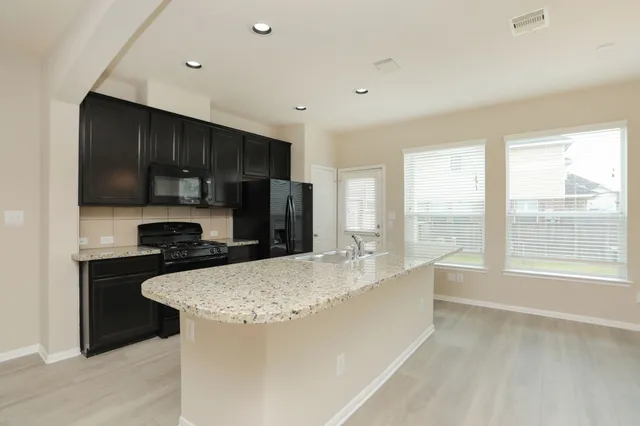 a kitchen with kitchen island a sink appliances and cabinets