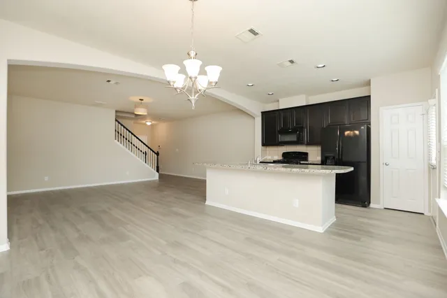 a view of a kitchen with kitchen island stainless steel appliances sink refrigerator dining table and chairs