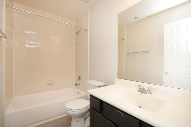 a bathroom with a bathtub shower sink mirror and toilet