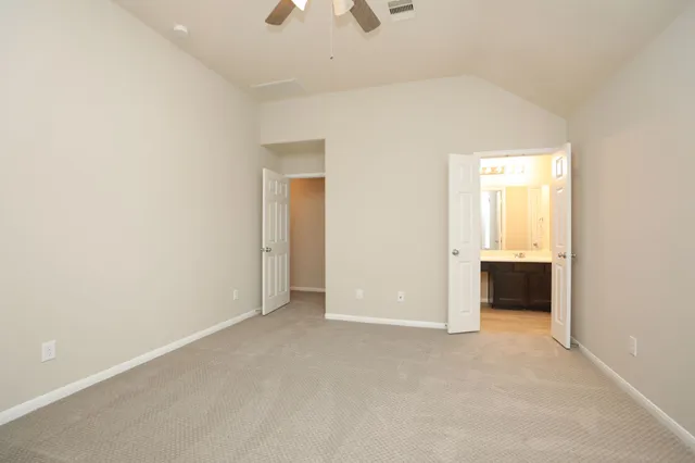 an empty room with an entryway and kitchen view
