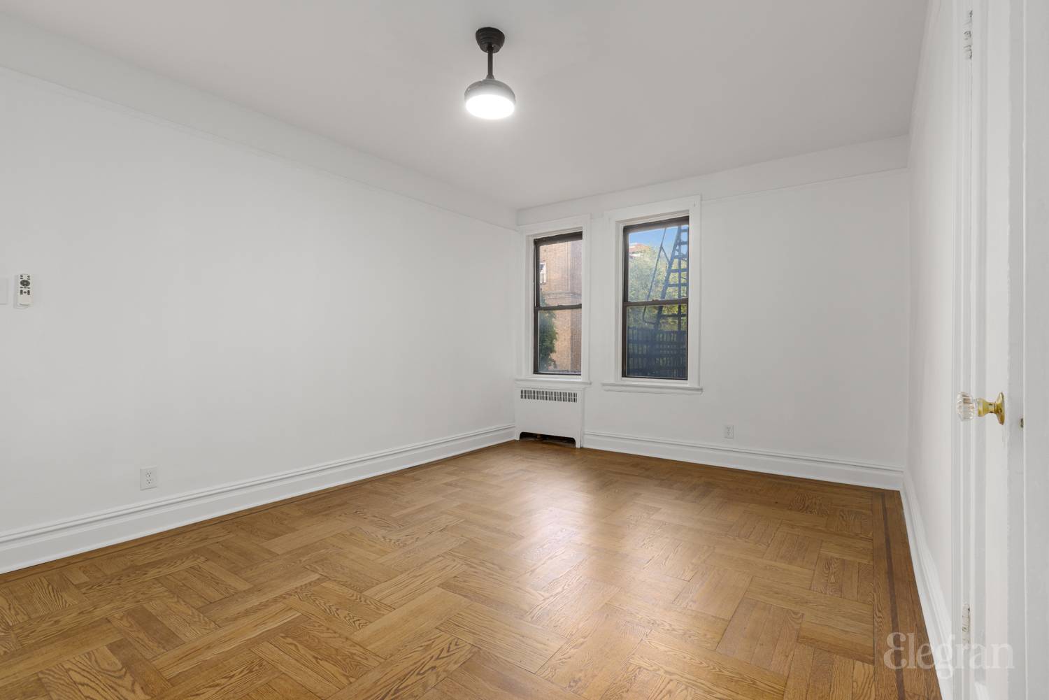 34-20 83rd Street, Unit 2I Queens, NY 11372 - Photo 8 of 9 an empty room with wooden floor and windows