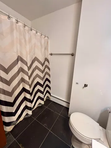a white toilet sitting next to a white curtain