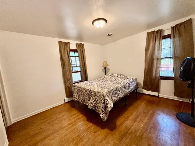 a bedroom with a bed window and wooden floor