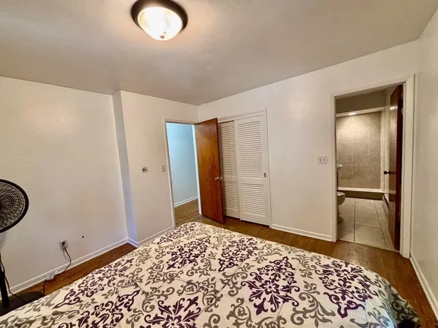 a view of a bedroom with wooden floor and bathroom