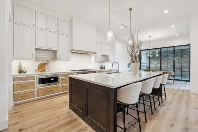 a kitchen with stainless steel appliances granite countertop a stove a sink a microwave a dining table and chairs with wooden floor