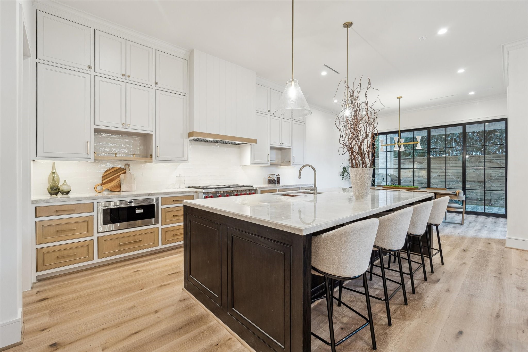 1210 West Drew Street Houston, TX 77006 - Photo 3 of 35 This kitchen is a chef's dream, showcasing hardwood floors, myriad storage, and dramatic quartzite countertops. Top-of-the-line appliances from Wolf, Sub Zero, and Bosch will elevate your cooking experience. The white backsplash and framing makes the darker tones of white oak drawers and island pop. Soft-close cabinets and drawers with gold pulls further elevate the space.
