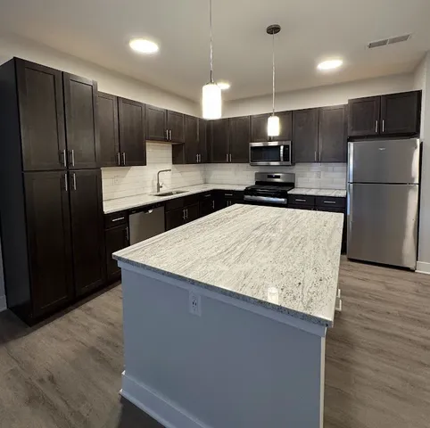 a kitchen with stainless steel appliances granite countertop a refrigerator and a stove top oven