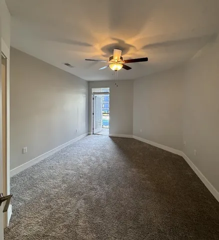 an empty room with chandelier fan and windows