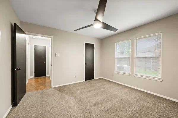 an empty room with windows and ceiling fan