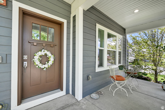 681 Island Road Morgan, UT 84050 - Photo 23 of 49 Inviting front porch featuring a brown entry door with transom window, gray horizontal siding, and white trim accents