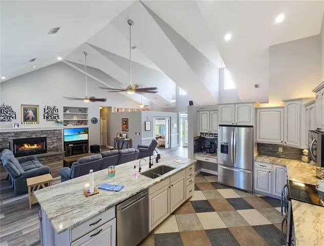 a kitchen with stainless steel appliances kitchen island granite countertop a sink refrigerator and cabinets