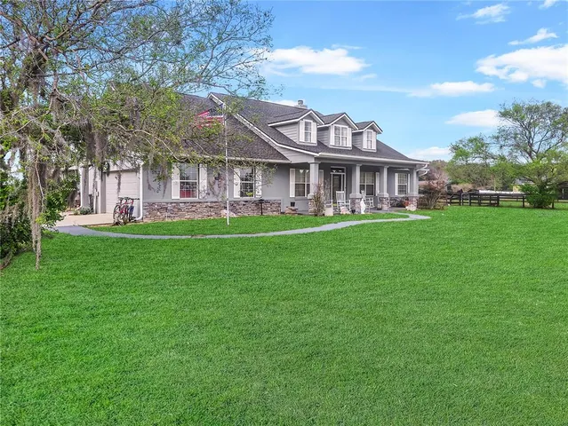a view of a house with a big yard and large trees