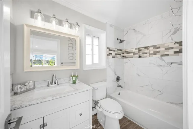a bathroom with a granite countertop sink toilet mirror and bathtub