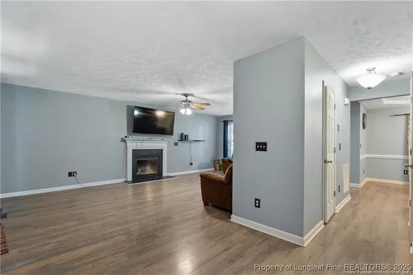 a view of a livingroom with a fireplace a ceiling fan and wooden floor