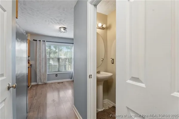 a view of a hallway with wooden floor and a bathroom