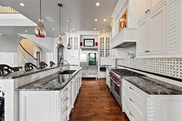 a kitchen with stainless steel appliances granite countertop a kitchen island a stove a sink a oven a dining table and chairs