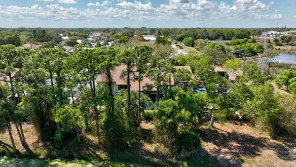 an aerial view of residential house with outdoor space and trees all around