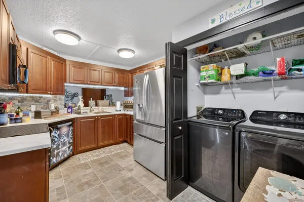 a kitchen with stainless steel appliances granite countertop a refrigerator a sink and wooden cabinets