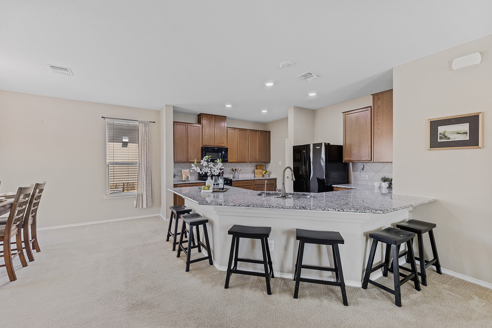 437 Sheepshank Drive Georgetown, TX 78633 - Photo 4 of 22 Granite counters and dark appliances highlight this spacious open-concept kitchen with a large prep surface that can double as a space for crafting or school projects.