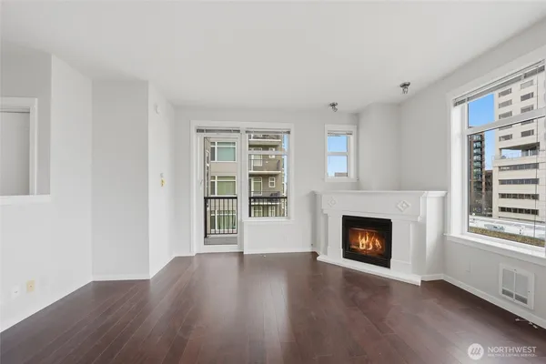 a view of an empty room with wooden floor fireplace and a window
