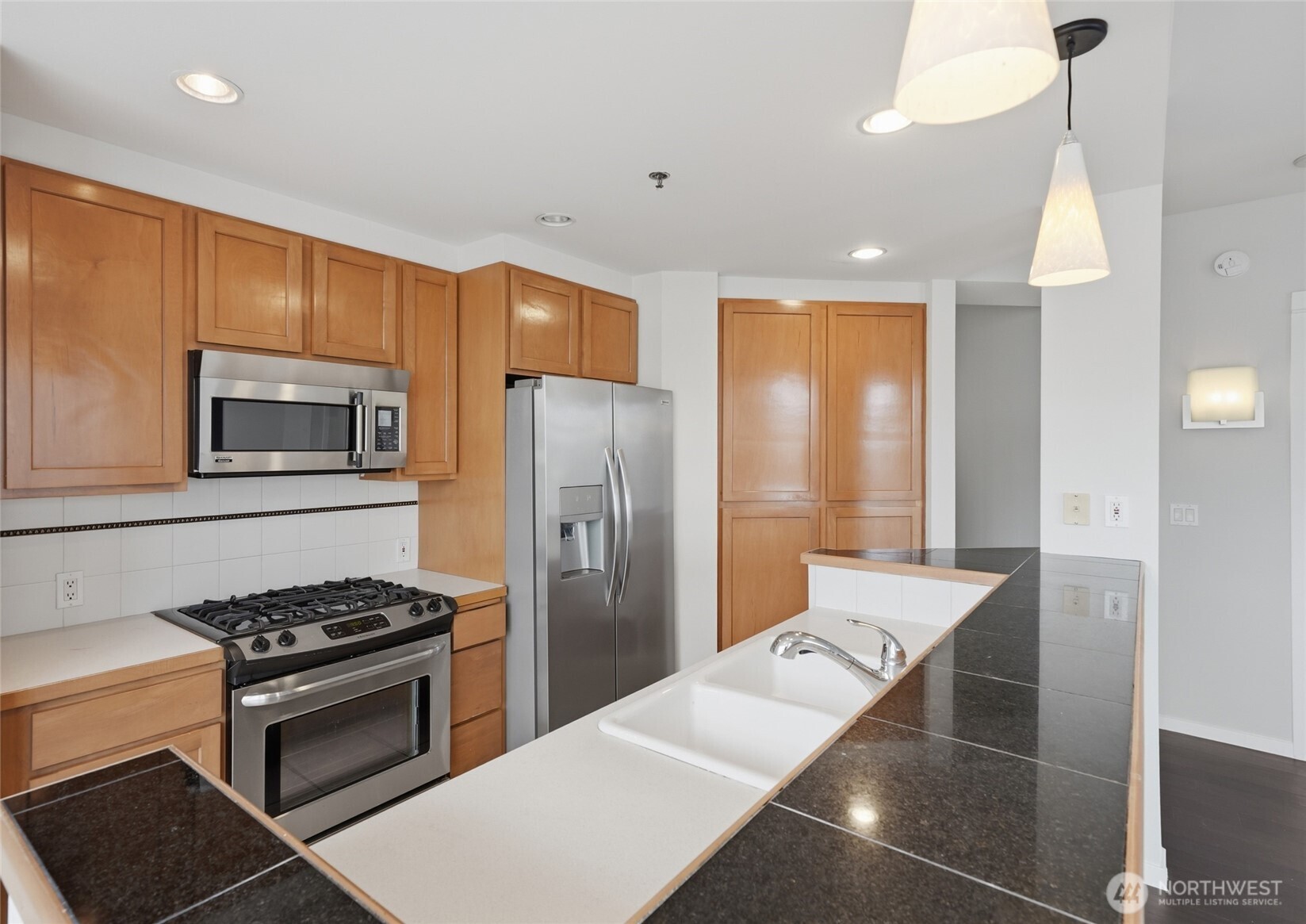 2801 1st Avenue, Unit 504 Seattle, WA 98121 - Photo 9 of 34 a kitchen with stainless steel appliances a refrigerator a stove and a sink