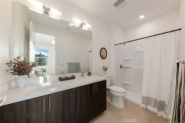 a bathroom with a double vanity sink toilet and shower