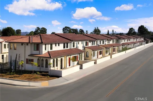 a view of a large white building among the street with houses