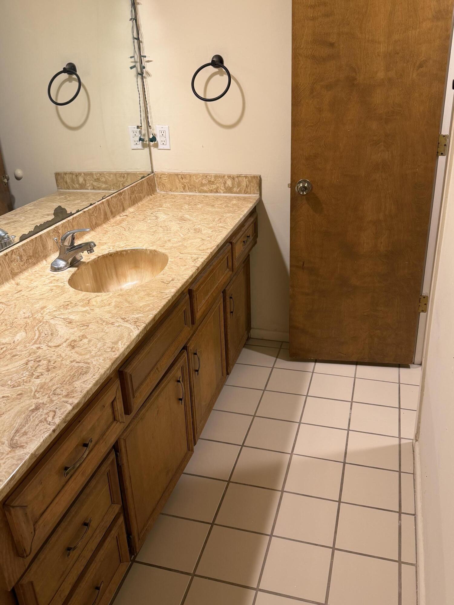 7203 Memphis Avenue, Unit B Lubbock, TX 79423 - Photo 8 of 13 a bathroom with a granite countertop sink and a mirror