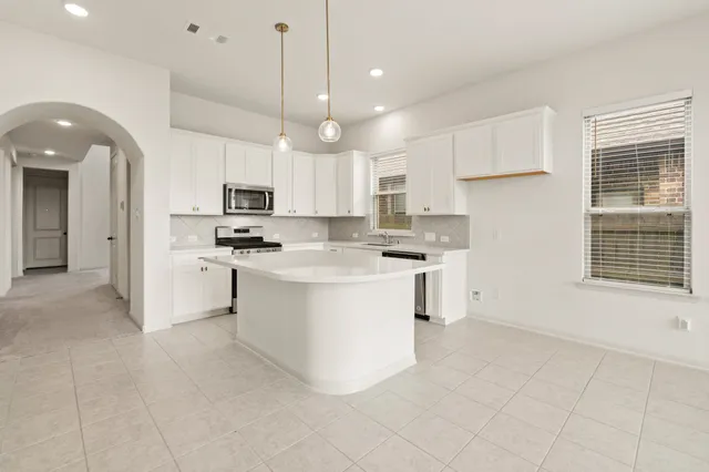 a kitchen with white cabinets and appliances