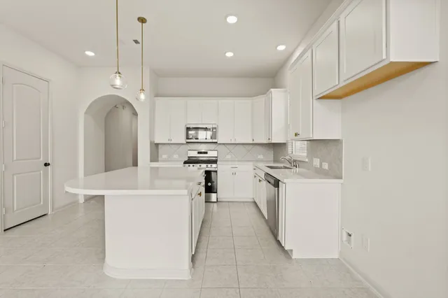 a kitchen with stainless steel appliances granite countertop a sink a stove and a refrigerator