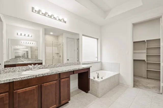 a bathroom with a granite countertop bathtub a double vanity sink and a large mirror