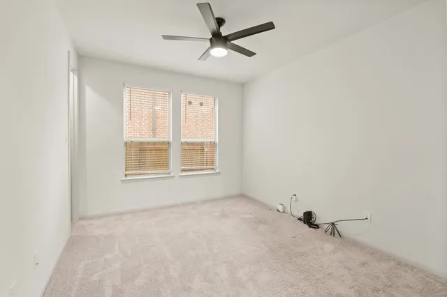 an empty room with a window and a fan