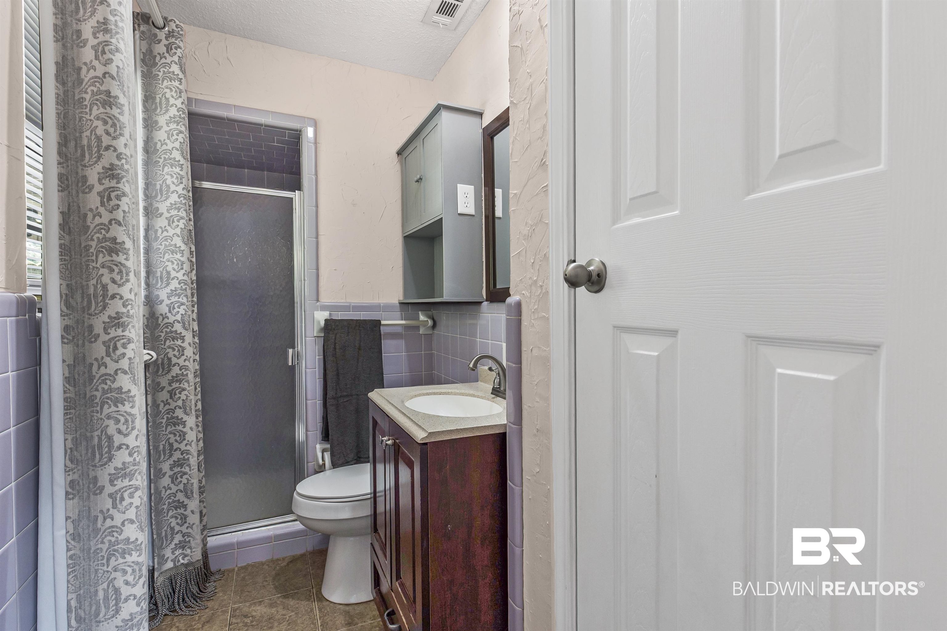 36 Ridgeview Drive Mobile, AL 36611 - Photo 10 of 20 Bathroom featuring vanity, a stall shower, tile walls, dark tile patterned flooring, and wainscoting