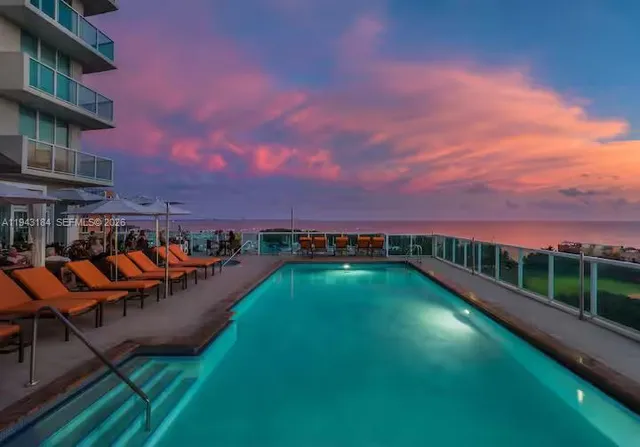 a view of a swimming pool with lawn chairs and plants