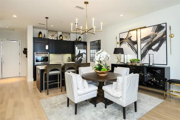 a kitchen with stainless steel appliances kitchen island granite countertop a refrigerator a stove a sink dishwasher and a dining table with wooden floor