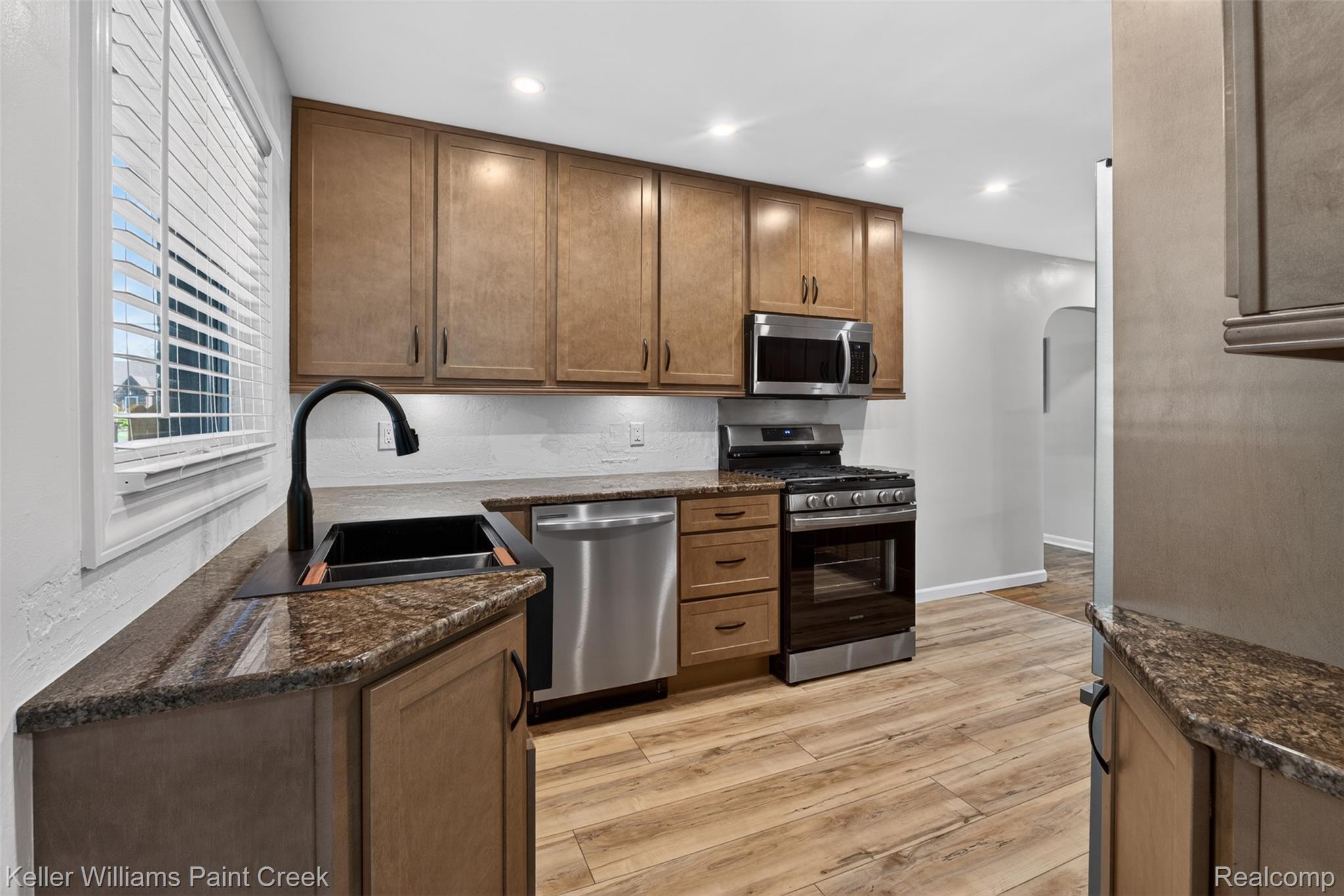 2942 Tatham Road Saginaw, MI 48601 - Photo 5 of 59 Kitchen featuring arched walkways, stainless steel appliances, dark stone countertops, and recessed lighting