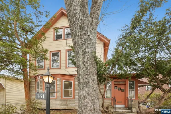a front view of a house with a tree