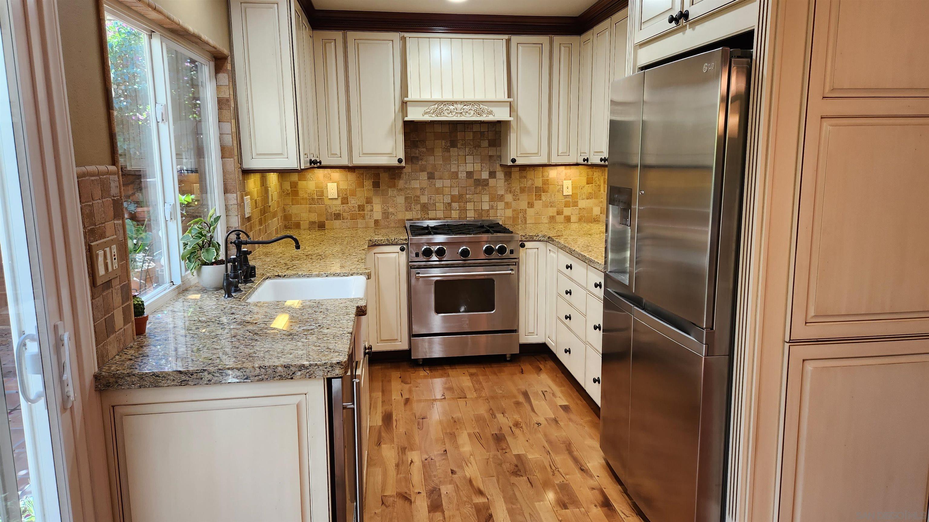 a kitchen with stainless steel appliances granite countertop a stove a refrigerator and a granite counter tops with white cabinets