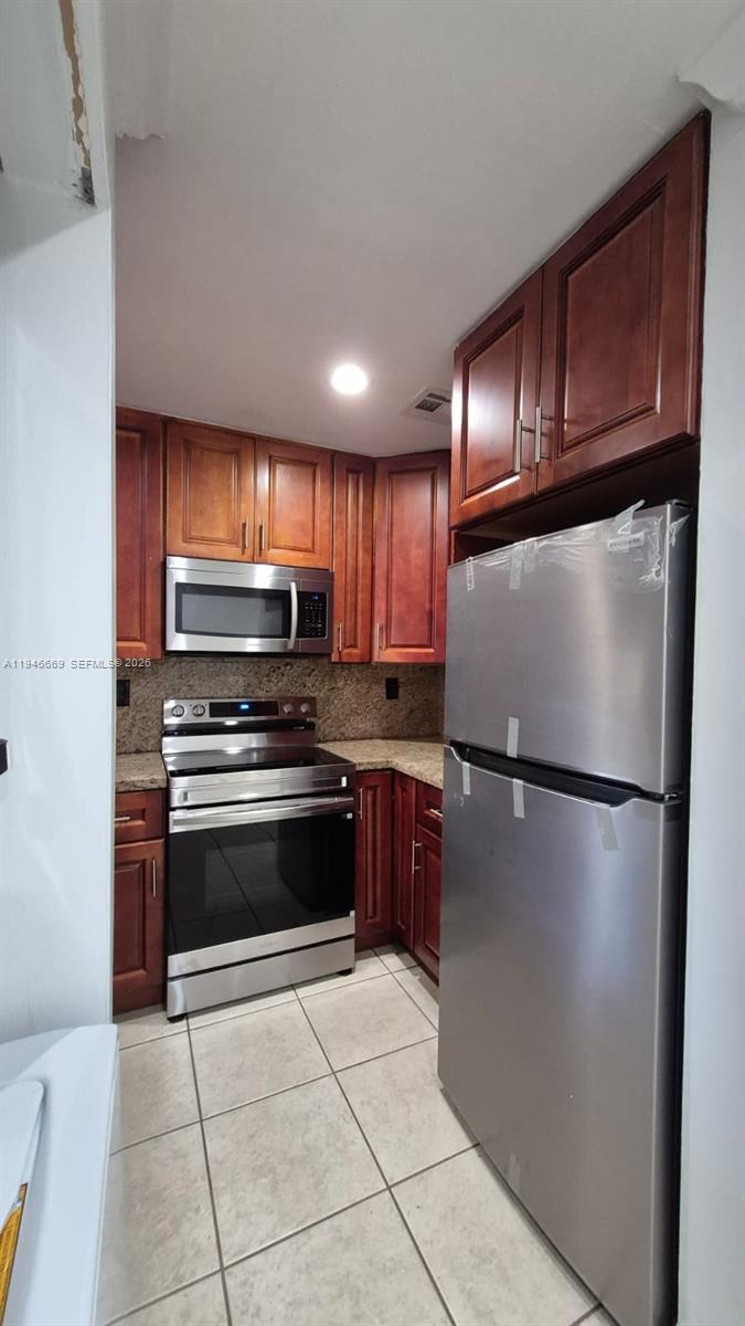 8531 Southwest 109th Avenue Miami, FL 33173 - Photo 2 of 19 a kitchen with granite countertop a refrigerator and a stove top oven