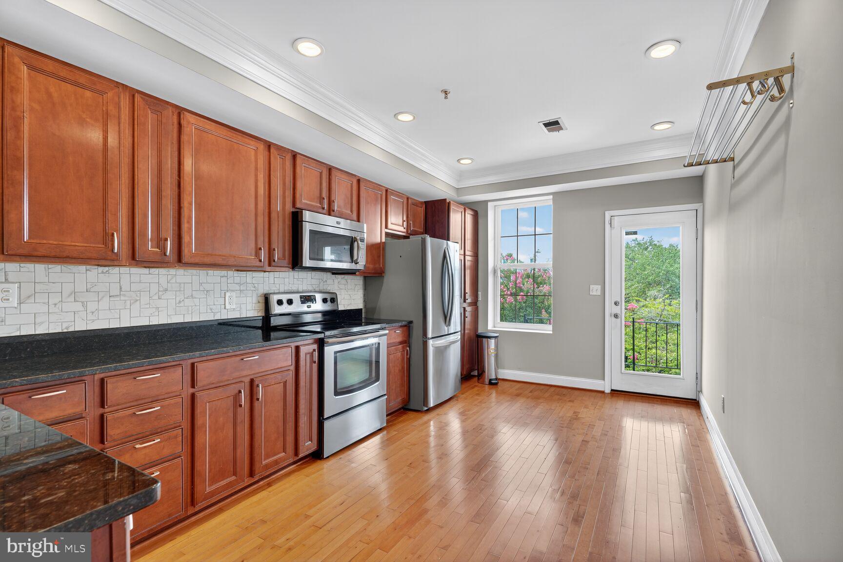 1730 1st Street Northwest, Unit 2 Washington, DC 20001 - Photo 7 of 27 a kitchen with stainless steel appliances granite countertop a refrigerator a stove top oven a sink and dishwasher with wooden floor