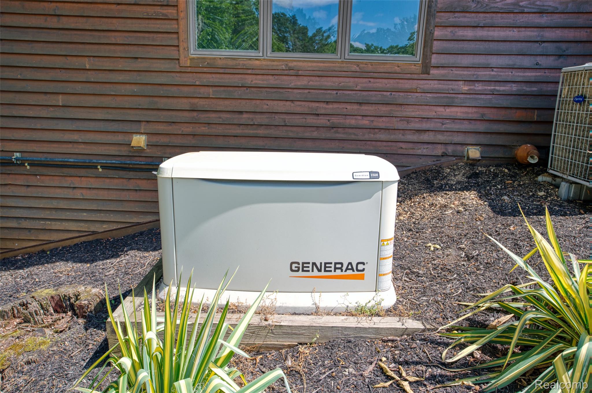 3166 Bigelow Road Howell, MI 48855 - Photo 33 of 50 Generac whole-house generator positioned on a concrete pad, complementing the horizontal wood siding exterior