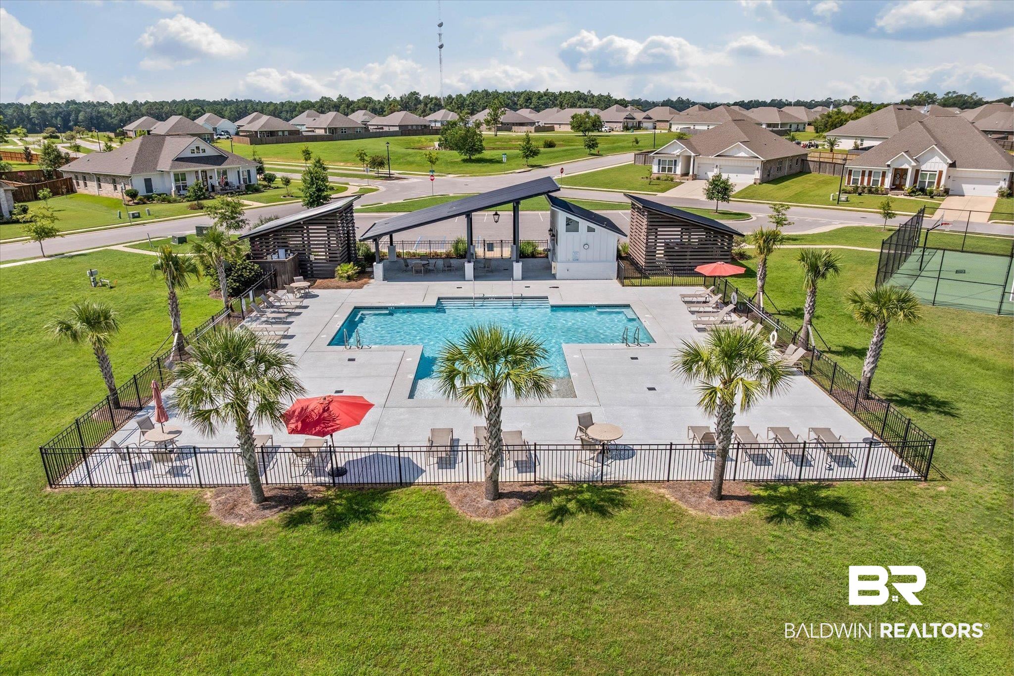 23523 Travis Stock Street Foley, AL 36535 - Photo 41 of 45 Community swimming pool with an expansive concrete deck, shaded cabanas, and surrounding palm trees