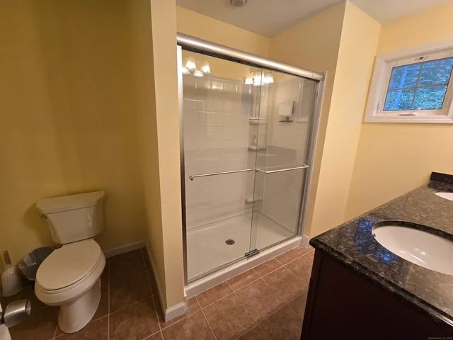 a bathroom with a granite countertop toilet and a shower