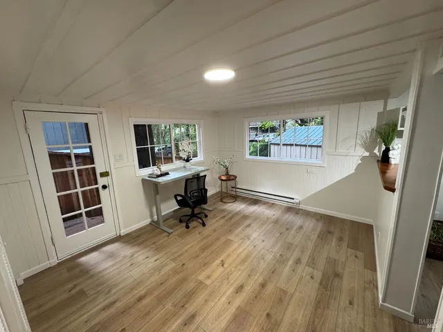 a view of a workspace with wooden floor and a window