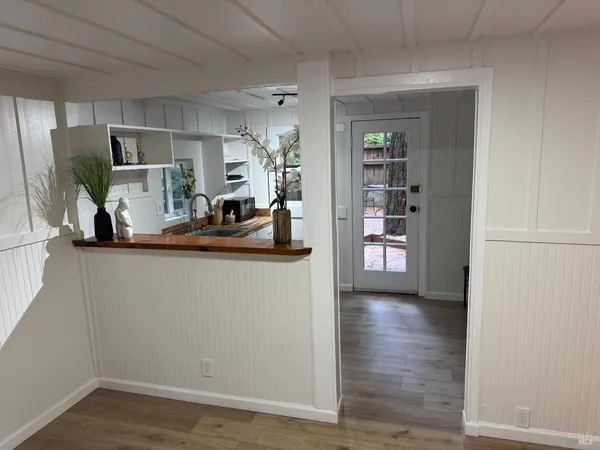 a view of a room with wooden floor and kitchen space