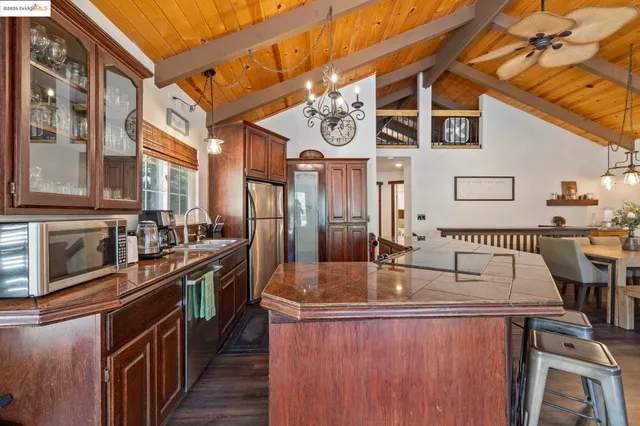 a kitchen with stainless steel appliances granite countertop a refrigerator a sink dishwasher a stove and white countertops with wooden floor