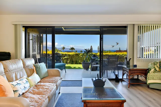 a living room with furniture a rug and a floor to ceiling window